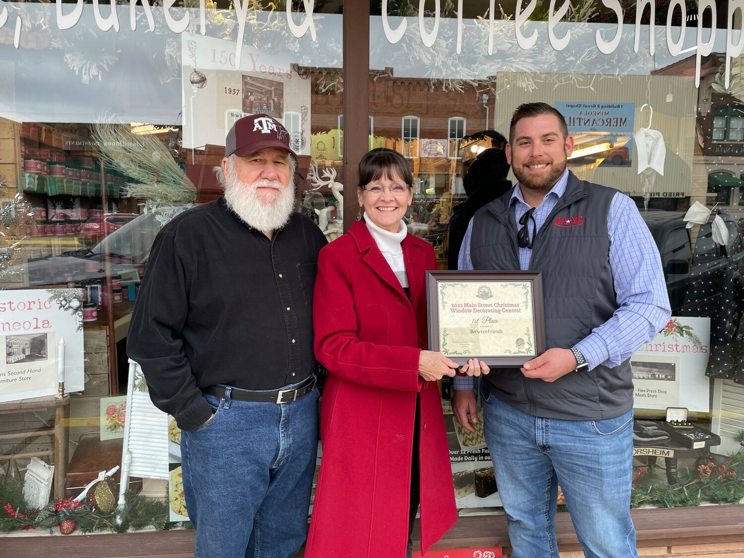 Main Street Chairman Nic Watkins presents the first place certificate to Donna and Charles Hanger.  Donna credits Charles and vendor Susan Smith with the winning windows.